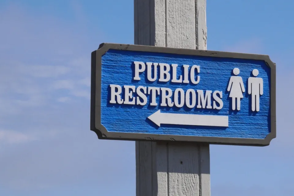 Blue "Public Restrooms" sign with arrow against a blue sky